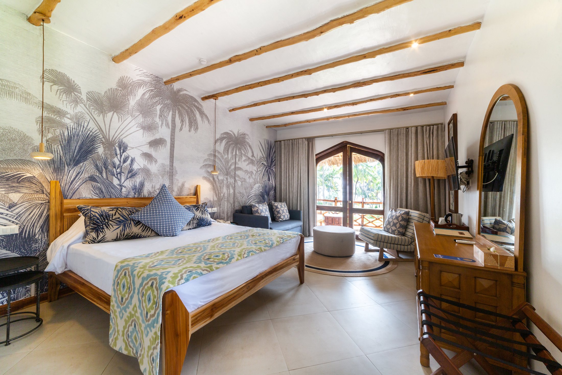 Ocean-view suite with a four-poster bed under a makuti roof, opening to the sea