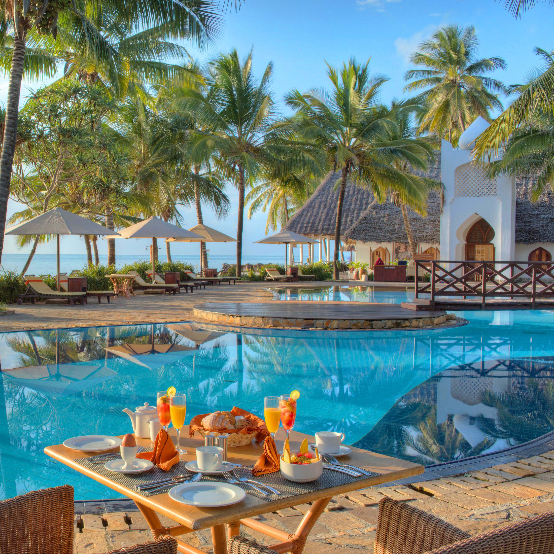 Beachfront pool with sun loungers and palms at Bluebay Beach Resort